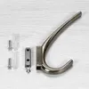 A single coat hook and its mounting hardware are laid out on a light-colored wooden surface. Produktbild-Vorschau