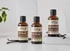 Three bottles of vanilla extract are displayed on a light-colored surface with some vanilla beans and a plant in the background. Náhled obrázku produktu