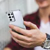 A person holding a smartphone with a clear case. Produktbild-Vorschau