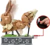 A LEGO-style Eevee figure with a mechanism to move its tail, shown with a finger pressing a button to activate the movement. Náhľad obrázku produktu