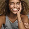 A woman wearing a grey tank top and a Pandora bracelet with a Wall-E charm. Podgląd zdjęcia produktu