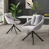 Two gray upholstered chairs with black metal legs are placed on a patterned gray carpet in a dining room setting. A white marble-top dining table is visible in the background, along with a large potted plant and a piece of abstract art on the wall. Podgląd zdjęcia produktu