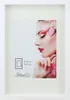 A white picture frame with a mat and a picture of a woman's face. Produktbild-Vorschau