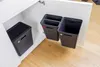 Two black trash bins are mounted on the inside of a cabinet door, with another black trash bin on the floor inside the cabinet. Produktbild-Vorschau