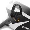 A close-up view of a black and white exercise bike pedal with a black strap and textured surface. Produktbild-Vorschau