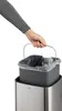 A hand is shown lifting a trash can liner out of a trash can. Podgląd zdjęcia produktu