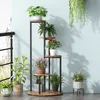 A multi-tiered plant stand filled with various potted plants, placed indoors near a window with a railing. Podgląd zdjęcia produktu