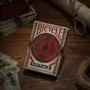 A deck of Bicycle Vintage playing cards is shown on a wooden table, with other cards and a rolled-up scroll in the background. Produktbild-Vorschau