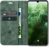 A green flip case for a smartphone is shown open, revealing card slots and a banknote, with the smartphone screen displaying the time and date. Produktbild-Vorschau