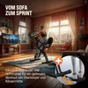A woman is exercising on a stationary bike in a living room with a TV and large windows. Produktbild-Vorschau