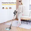 A woman is using a cordless vacuum cleaner in a living room. Produktbild-Vorschau
