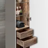 A close-up view of an open bathroom cabinet, showing shelves with toiletries, a folded towel, and two wooden drawers. Produktbild-Vorschau