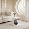A modern living room with a white sofa, a white coffee table with a pet bed integrated into its base, and a large circular window with sheer curtains. Produktbild-Vorschau
