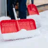 A person is shoveling snow with a red snow shovel. Náhled obrázku produktu