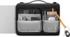 An open black laptop bag with various tech accessories organized inside, next to a silver laptop. Produktbild-Vorschau
