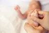 A close-up of a baby's foot being massaged by an adult's hands. Podgląd zdjęcia produktu