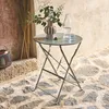 A folding bistro table set up outdoors on a stone patio, with a vase of greenery, a bottle of water, and a glass on the table. Anteprima dell’immagine prodotto