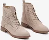 A pair of beige lace-up ankle boots with laser-cut floral detailing. Voir les images du produit
