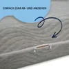 Close-up of a gray mattress cover with a zipper, showing a blue arrow pointing to the zipper and text indicating ease of use. Produktbild-Vorschau
