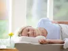 A woman sleeping peacefully on a pillow next to a window. Produktbild-Vorschau