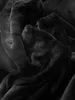 A close-up, abstract view of a black, plush fabric, likely a blanket or bedsheet, showing its soft texture and folds. Produktbild-Vorschau