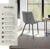 A gray upholstered chair with black legs is shown in a room with a window and a small side table. Produktbild-Vorschau