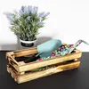 A wooden crate filled with gardening tools and a potted plant. Produktbild-Vorschau