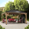 An outdoor patio scene featuring a wooden gazebo with outdoor furniture and a fireplace. Náhled obrázku produktu