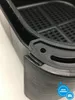 A close-up view of the corner of a black air fryer basket, showing the textured exterior and the rim. Produktbild-Vorschau