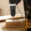 A person is using a cordless drill to drill into a piece of wood, with wood shavings scattered around. Produktbild-Vorschau
