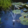 A solar-powered fountain with LED lights operating in a pond with lily pads and grass. Produktbild-Vorschau