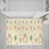 A baby play mat with animal illustrations is laid out on a wooden floor next to a crib. Náhľad obrázku produktu