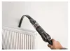 A hand is using a vacuum cleaner to clean a radiator. Produktbild-Vorschau