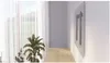 A wall mount for a TV is shown mounted on a wall in a hallway, with sheer curtains and a plant in the foreground. Anteprima dell’immagine prodotto