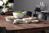 A dining table set with various white ceramic bowls filled with food and flowers in a vase. Podgląd zdjęcia produktu