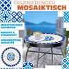 A mosaic bistro table with a cup of coffee on it, set against a blurred background of a Mediterranean-style town and sea. Produktbild-Vorschau