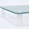 A close-up, low-angle shot of the edge of a glass cutting board with clear plastic feet. Anteprima dell’immagine prodotto