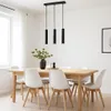 A dining room with a wooden table and white chairs, illuminated by a black pendant light fixture. Náhled obrázku produktu