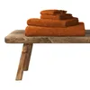 A stack of orange towels on a wooden bench. Produktbild-Vorschau