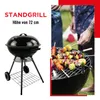 A black charcoal grill with food on skewers being cooked. Produktbild-Vorschau