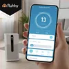 A hand holding a smartphone displaying an air purifier app, with the air purifier device visible in the background. Náhled obrázku produktu