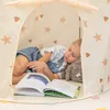 A young girl is sleeping inside a play tent with a book open next to her. Náhled obrázku produktu