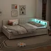 A bedroom scene with a beige sofa bed, decorated with pillows and blankets, and illuminated by LED lights. Náhled obrázku produktu