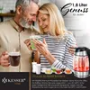 A couple enjoying hot beverages, with a kettle and cups in the foreground. Produktbild-Vorschau
