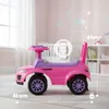 A pink and purple ride-on toy car for children, shown in a nursery or playroom setting with a crib and shelves in the background. Produktbild-Vorschau