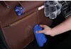 A hand is cleaning a brown car seat organizer with a blue cloth. Podgląd zdjęcia produktu