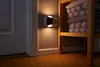 A night light plugged into a wall socket, illuminating a hallway with stacked towels on a shelf nearby. Produktbild-Vorschau
