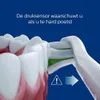 Close-up of an electric toothbrush head cleaning teeth, with a warning symbol and arrow indicating pressure. Voir les images du produit