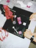 A table with various items, including pink squares with numbers, a red ribbon, and a black tray with liquid. Náhľad obrázku produktu