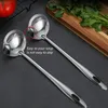 Two stainless steel ladles are shown on a dark surface, with a wooden cutting board and cilantro in the background. Produktbild-Vorschau